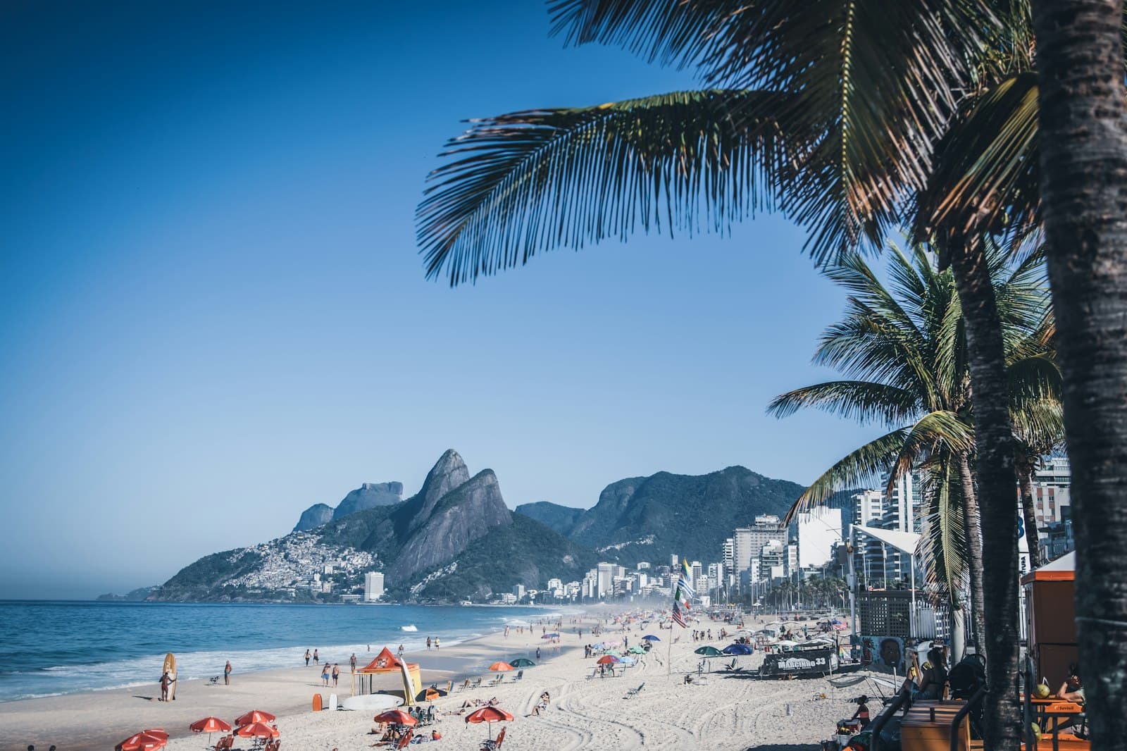 A busy beach in Rio de Janeiro with the mountains behind