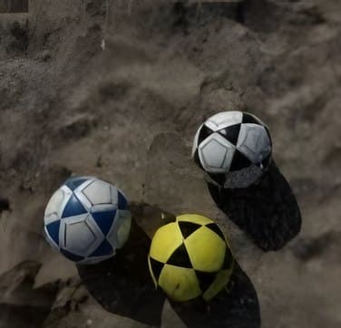 Three footvolley balls resting in the sand